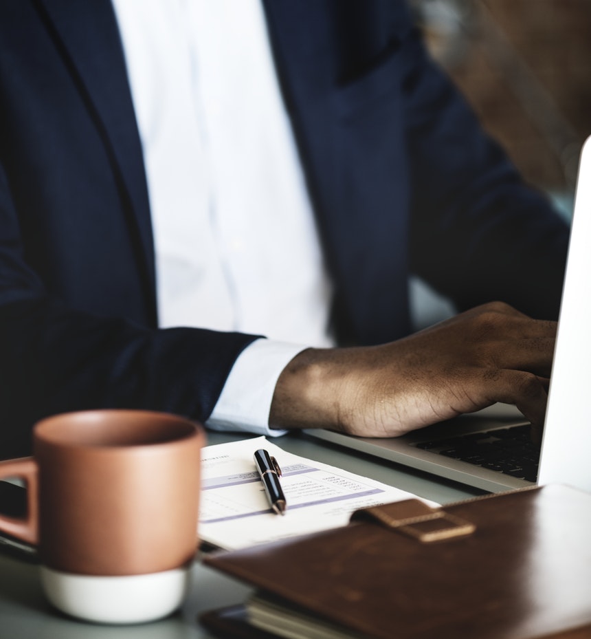 a man with blue coat is writing an article about resume writers while drinking coffee