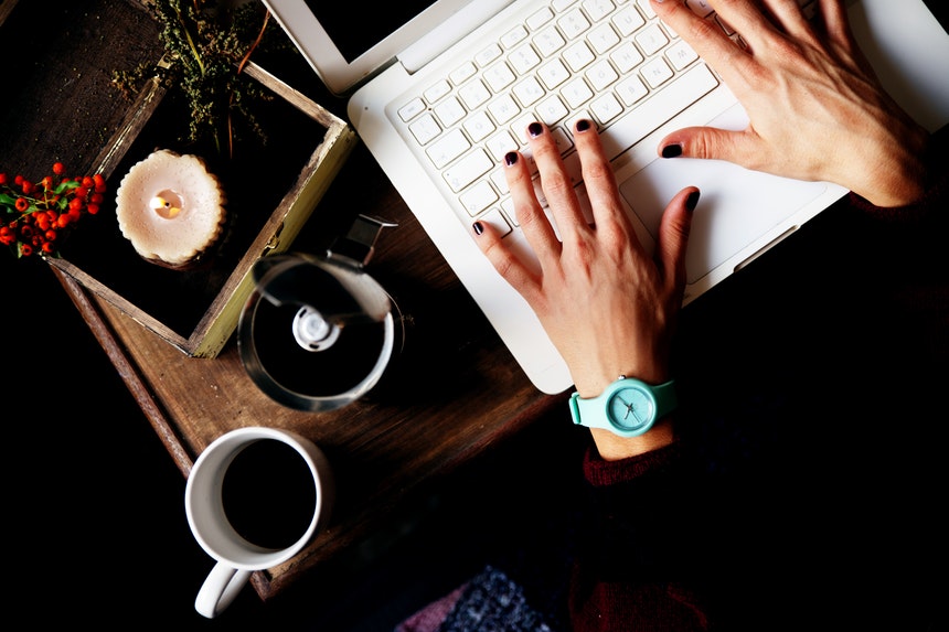 A woman is typing an article in her laptop about resume writers