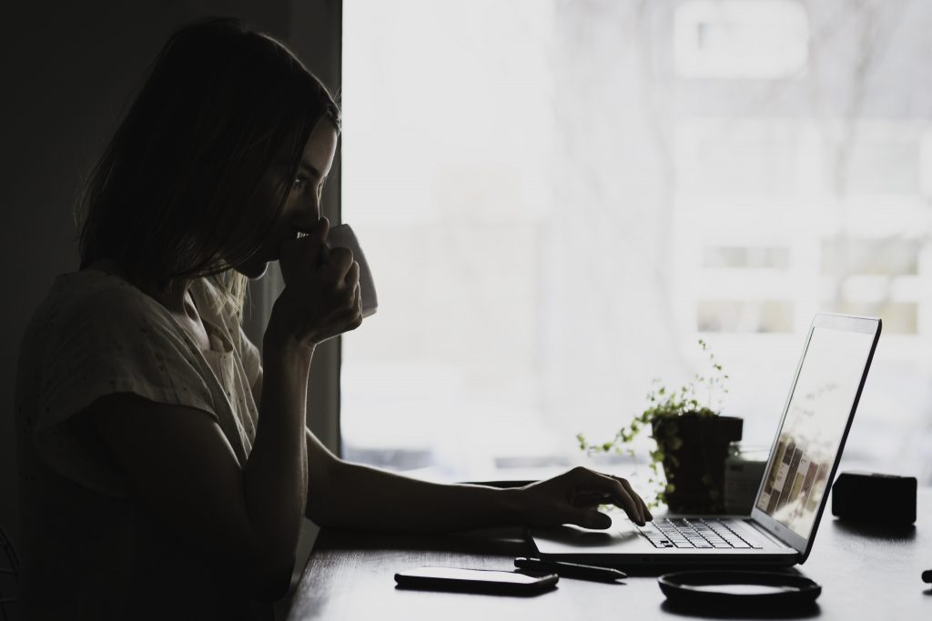 working with a laptop while sipping a cup of coffee