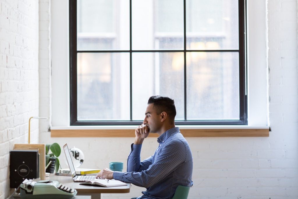 man searching on his laptop for the best resume writing service provider