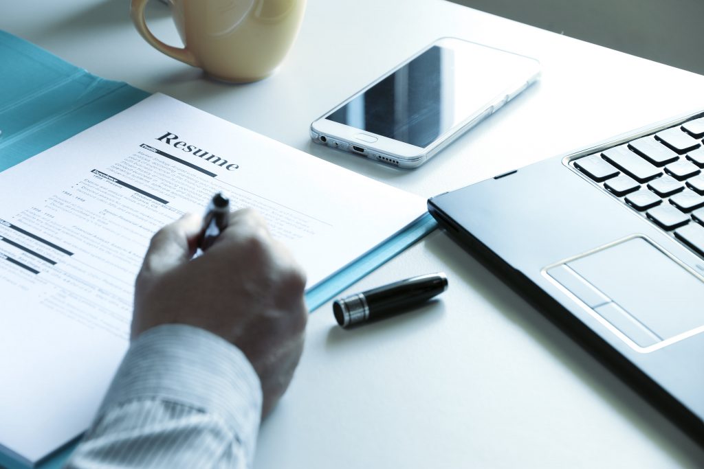 A professional writing his long resume on a desk