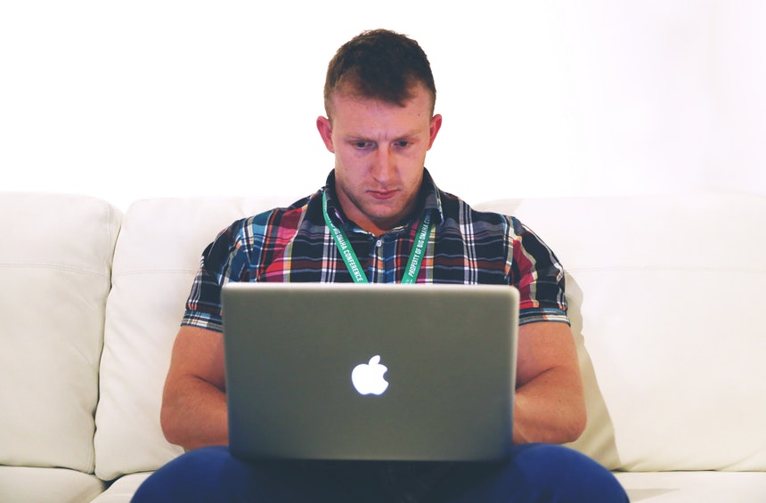 Male jobseeker looking for linkedin profile writing tips on his Mac laptop