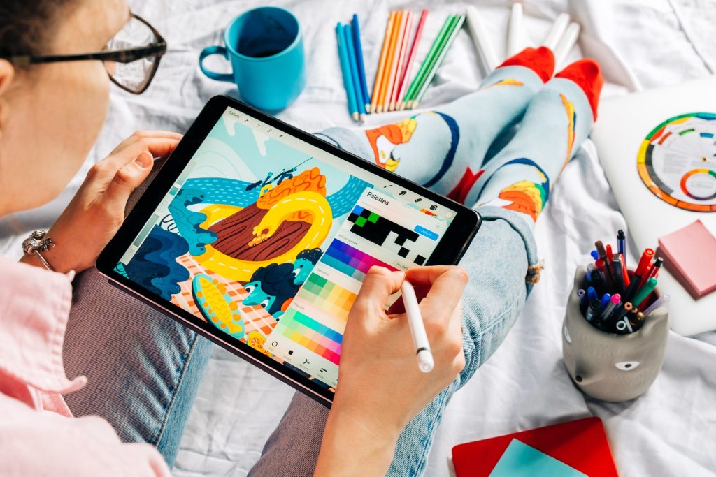 graphic artist drawing sketches and colorful illustrations on her iPad
