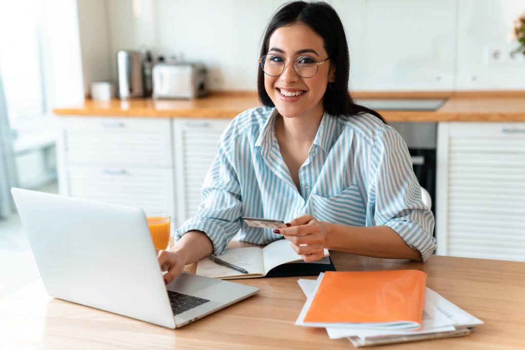 woman using laptop computer holding credit card AU7RX7S 1 2